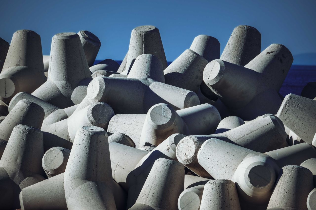 Photo of abstract concrete breakwater structures against a deep blue sky.