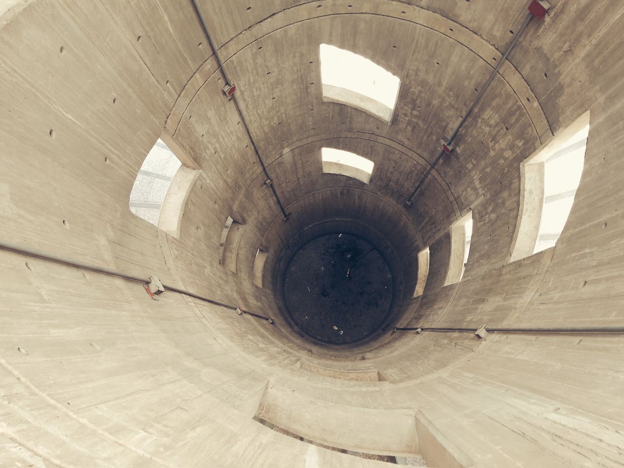 A downward perspective inside a massive concrete silo with geometric windows.